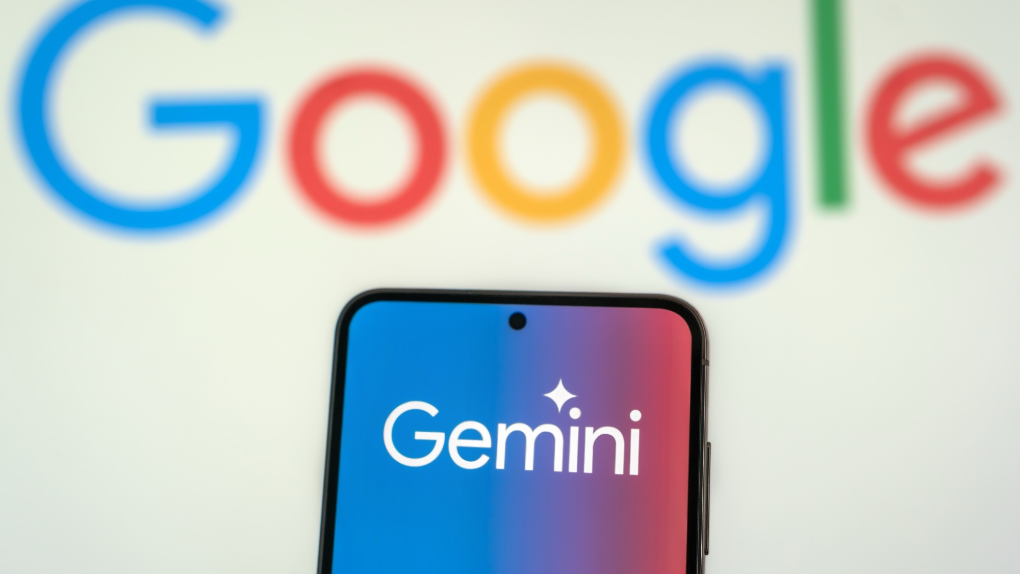 智能手机上的 Gemini 标志，背后是 Google 标志。
